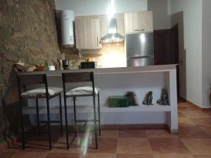 a kitchen with a counter with stools and a refrigerator at Casa Rural El Turuterro in Cepeda