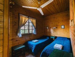 two beds in a log cabin with a window at Cabañas del Golf in Sierra de la Ventana