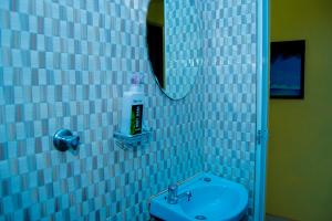 uma casa de banho em azulejos azuis com um lavatório e um espelho em Magnolia Cosy 1 Bedroom Apartment-KILIFI em Kilifi