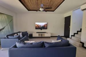 sala de estar con 2 sofás azules y TV de pantalla plana en Casa Cardumen - Ciudad Del Mar, in Jaco, en Jacó