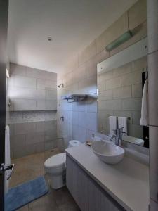 a bathroom with a white toilet and a sink at Casa Cardumen - Ciudad Del Mar, in Jaco in Jacó