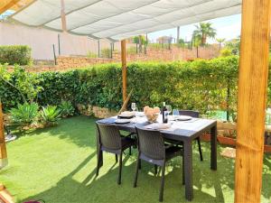 einen Tisch und Stühle unter einem Sonnenschirm in einem Garten in der Unterkunft Apartamento con hermoso jardín y AC in Isla Plana