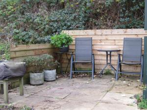 a patio with two chairs and a table and a fence at The Spring Slad Valley Cotswolds in Painswick
