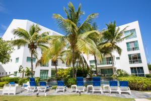 une rangée de chaises et de palmiers devant un bâtiment dans l'établissement Cap Cana 3br Full Kitchen, Wifi, Smart Check-in, à Punta Cana