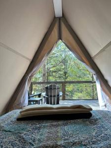 - une chambre avec un lit dans une tente avec une fenêtre dans l'établissement Bohamia - Cozy A-Frame Glamp on 268 acre forest retreat, à Talladega