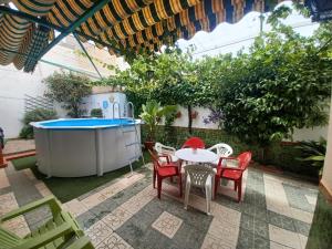 un patio con mesa, sillas y piscina en El Rincón de la Rosa, en La Zubia