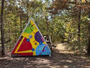 a triangular tent sitting in the middle of a forest at Bohamia - Cozy A-Frame Glamp on 268 acre forest retreat in Talladega