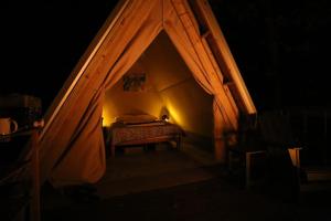 een slaapkamer met een bed in een tent in het donker bij Bohamia - Cozy A-Frame Glamp on 268 acre forest retreat in Talladega