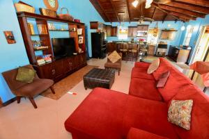 a living room with a red couch and a kitchen at Caribbean Shores Belize in Hopkins