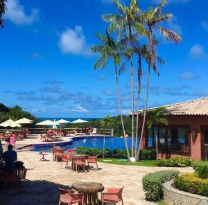une piscine au complexe avec tables, chaises et palmiers dans l'établissement Prime Villas do pratagy, à Maceió