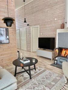 a living room with a table and a fireplace at Villa Laidike with sauna/fireplace, 80 km Helsinki in Suomusjärvi