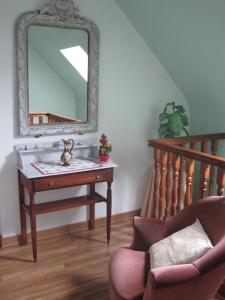 Un espejo en una pared encima de una mesa con una silla. en Chambres d'hôtes La Pinderie, en Val Couesnon