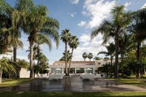 un bâtiment avec des palmiers en face de celui-ci dans l'établissement Villa Carlino House, à Mascali