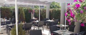 a restaurant with tables and chairs and purple flowers at Cottage Logis H&ocirc;tel - Restaurant in Dudelange