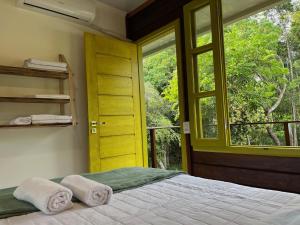 um quarto com uma cama, uma porta amarela e uma janela em Chalés Mata da Praia Corumbau em Corumbau