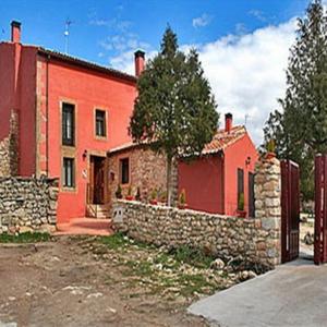 una casa rossa con un muro di pietra accanto a un edificio di La Perseverancia a Aldehuela