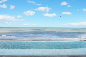 una piscina junto a una playa con el océano en Los Pinos Pinamar 3c en Pinamar