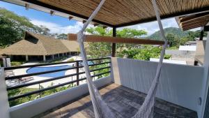 a view from the balcony of a resort with a hammock at Casa Cardumen - Ciudad Del Mar, in Jaco in Jacó