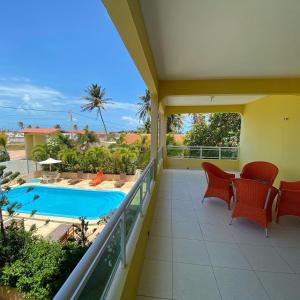 a balcony with a table and chairs and a swimming pool at Pousada Vitoria Aquiraz in Aquiraz