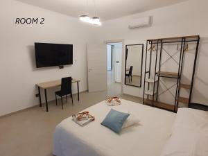 Habitación con cama, mesa y TV. en Il Giardino dei Sorrisi en Ostuni