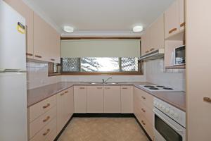 a kitchen with white cabinets and a sink and a window at Quarterdeck 9 in Port Macquarie