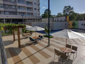 a patio with tables and chairs and umbrellas at Recanto do Bosque FLAT 205 in Caldas Novas