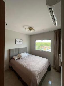 a bedroom with a large bed with a window at Recanto do Bosque FLAT 205 in Caldas Novas
