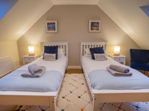 two beds in a attic room with two lamps at Heatherlea in Carinish