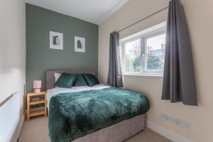 ein Schlafzimmer mit einem Bett mit einer grünen Bettdecke und einem Fenster in der Unterkunft Milton Stays - Cosy Home in Central York for 6 With On Street Parking in York