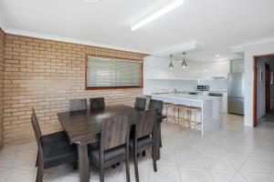 cocina y comedor con mesa de madera y sillas en 31 Cornwallis Close, en Port Macquarie