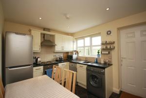 a kitchen with a refrigerator and a sink and a table at House Martins Beadnell in Beadnell