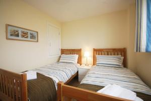 two beds in a small room with a lamp at House Martins Beadnell in Beadnell