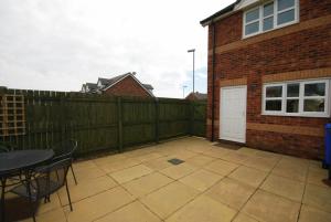 a patio with a wooden fence and a white door at House Martins Beadnell in Beadnell