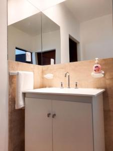 y baño con lavabo blanco y espejo. en Servando Deptos turísticos en San Rafael