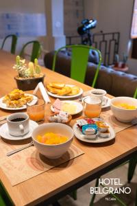 een houten tafel met kommen en borden met eten erop bij Hotel Belgrano in Tilcara