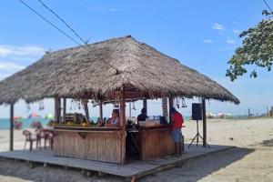 un bar en la playa con una cabaña de paja en La Casa de la Playa, en Atacames