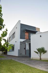 Una casa blanca con un árbol delante. en Servando Deptos turísticos en San Rafael