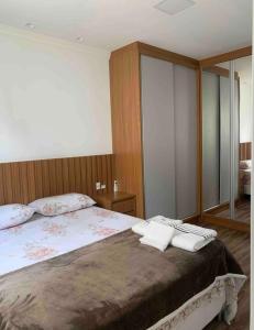 Un dormitorio con una cama grande con dos toallas encima. en Apartamento 3 suítes a 100m do mar, en Itapema