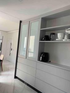 Una cocina con gabinetes blancos y una ventana grande. en Apartamento 3 suítes a 100m do mar, en Itapema