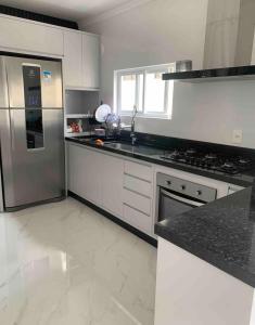 a kitchen with white cabinets and a stainless steel refrigerator at Apartamento 3 suítes 1 quadra do mar in Itapema