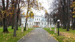 une maison blanche avec des arbres devant elle dans l'établissement Pałac Chojnata, à Wola Chojnata