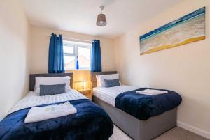 two beds in a room with blue curtains at 4 Bed House in Castle Donington (EMA) with parking in Castle Donington