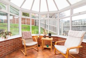 two chairs and a table in a conservatory with windows at 4 Bed House in Castle Donington (EMA) with parking in Castle Donington
