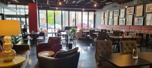 Un restaurante con mesas, sillas y ventanas. en The Arts Hotel, en Charlottetown