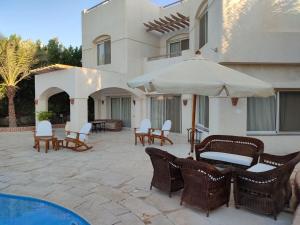 patio z krzesłami i parasolem obok budynku w obiekcie GS 18 Villa w mieście Hurghada