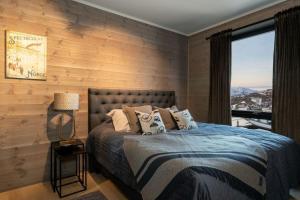 1 dormitorio con 1 cama con pared de madera en Splitter ny leilighet med panoramautsikt en Beitostøl