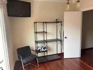 a room with a chair and a shelf and a television at Casa con encanto in Cariño