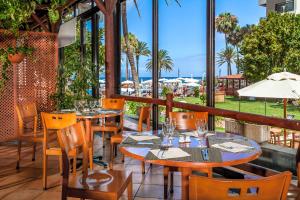 a restaurant with tables and chairs and a view of the ocean at Sol Tenerife in Playa de las Americas