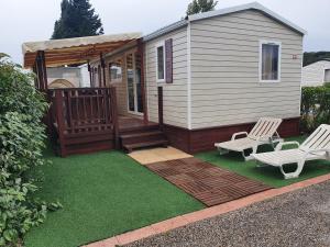 a backyard with a cabin with a deck and two chairs at Mobil home MAXI CONFORT SUR LA COTE D'AZUR in Fréjus