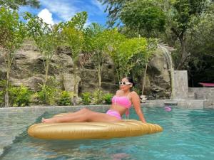 una mujer en bikini sentada en una balsa en una piscina en Tuku,, en Guarinocito